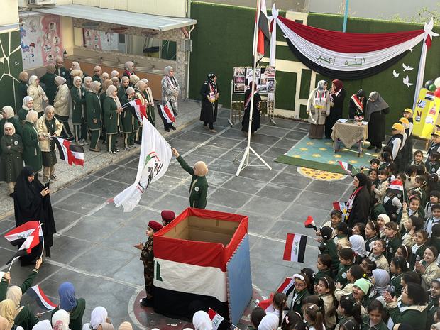 طالبة ترفع العلم العراقي في احتفال المناسبة الوطنية