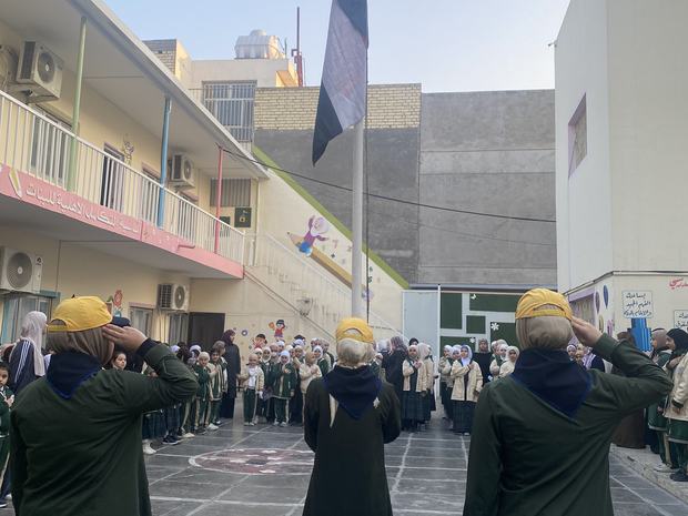 طالبات يؤدّين التحية في ساحة المدرسة