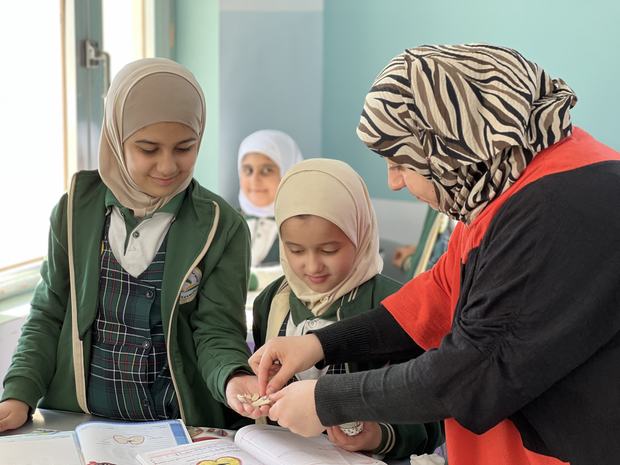 معلّمة تتابع طالباتها أثناء الدرس