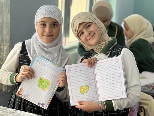 طالبتان تعرضان دفتريهما بعد إنجاز الواجب