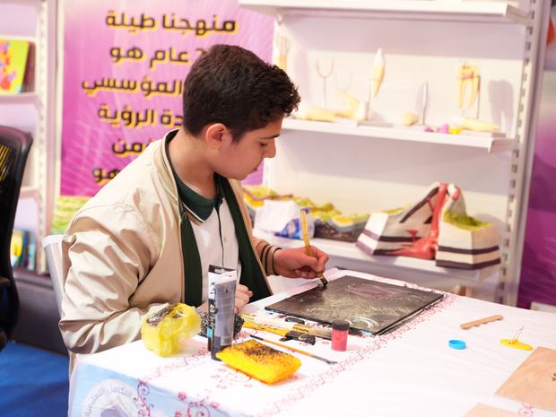 طالب يعرض مهاراته الفنية في جناح المعرض