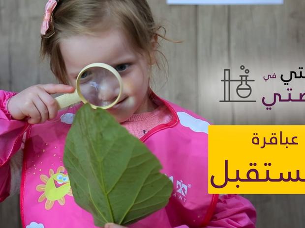 طفلة تتفحّص ورقة نبات بالعدسة المكبّرة