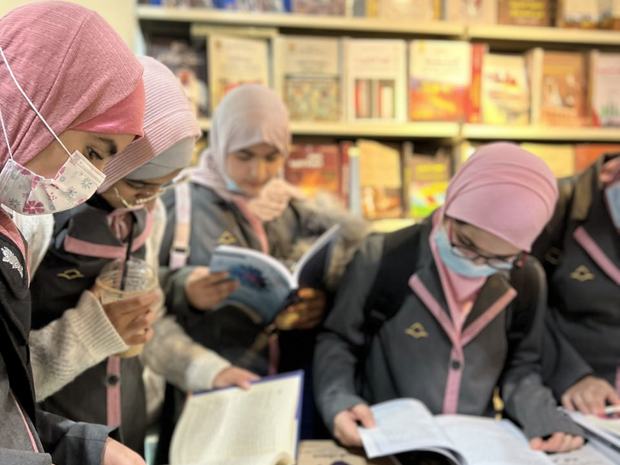 طالبات يقرأن بين رفوف المكتبة